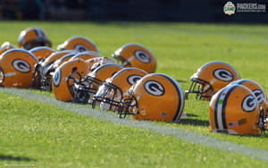 Green Bay Packers頭盔排列喺草地足球場上。