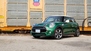 綠色MINI Cooper S停泊在一輛黃色貨運火車車廂旁邊。 — 汽車 壁紙