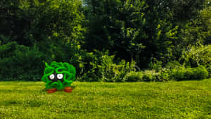 一個有大眼睛的綠色卡通生物，站在樹木附近的草地上。