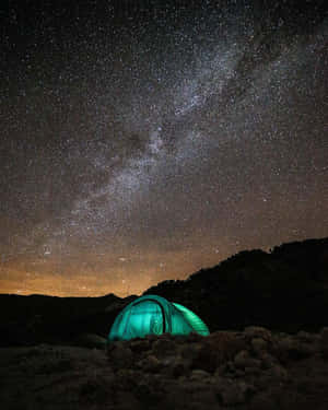 在星空夜空下，一頂發光的綠色帳篷，銀河清晰可見。
