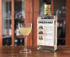 一瓶Green Hat氈酒和木製吧枱上的雞尾酒。