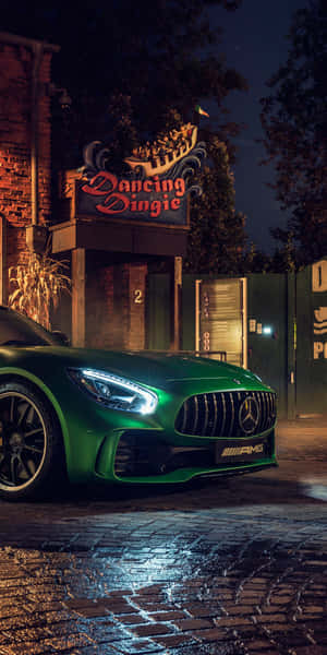 夜間在霓虹燈下停泊在濕漉漉的鵝卵石街道上的綠色 Mercedes-AMG。 — 汽車 壁紙