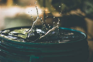 水滴在玻璃碗中向上濺起，背景模糊。