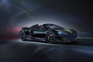 在黑暗的工作室環境中，黑色McLaren跑車帶有綠色亮點。