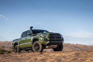 日落時分，橄欖綠色的豐田 Tacoma TRD Pro 停泊在岩石沙漠地形上。