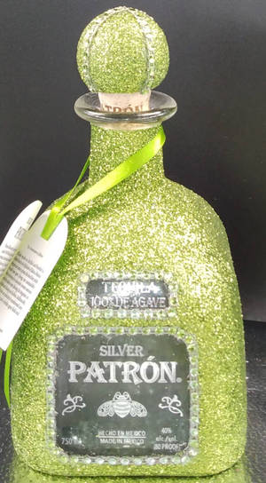 一個帶有絲帶和標籤的閃亮綠色 Patron 龍舌蘭酒瓶。