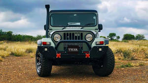 綠色Mahindra Thar SUV停泊在草地泥路上的正面視圖。