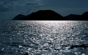 暮色中，暗色島嶼在閃爍的海面上形成剪影。 — 美景 壁紙