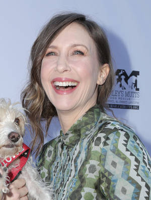 女性在Marley's Mutts活動中抱著白色小狗，笑容燦爛 — 荷里活 GIF 壁紙