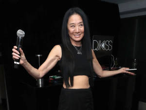 微笑女性在帶有DJ KISS標誌的DJ台拿著麥克風和平板電腦。