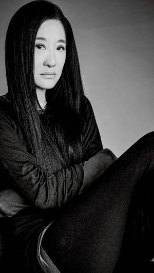 一位長髮深色頭髮的女性在工作室肖像中平靜地坐著。 — 黑白 壁紙