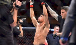 MMA 拳手在八角籠內高舉雙臂慶祝勝利。