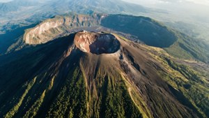 一個火山口嘅航拍圖，斜坡被灰燼覆蓋，周圍係綠色森林。