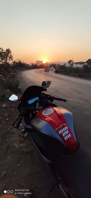 夕陽下，紅黑色電單車停在路邊，遠處有建築物。