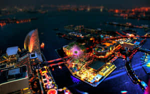 夜間空中景觀，一個發光的港口，有摩天輪和城市燈光。 — 天際線 壁紙