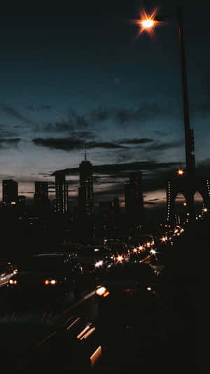 黃昏時分的城市天際線，橋上有發光的街燈和汽車頭燈。 — 夜晚 GIF 壁紙