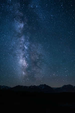 在繁星點點的夜空下，銀河系在白雪覆蓋的山峰上方閃耀。 — POCO Pad 壁紙