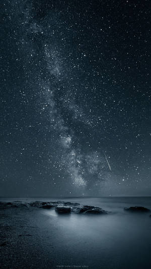 銀河與流星在夜間深色海洋岩石上方 — iPhone 動態 GIF 壁紙