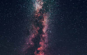 銀河系在繁星點點的夜空中散發粉紅和藍綠色星雲的光芒。