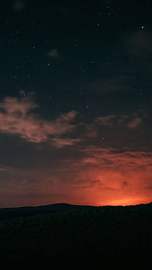 繁星點點的夜空，森林剪影上方有橙色雲彩。 — 夜空 壁紙
