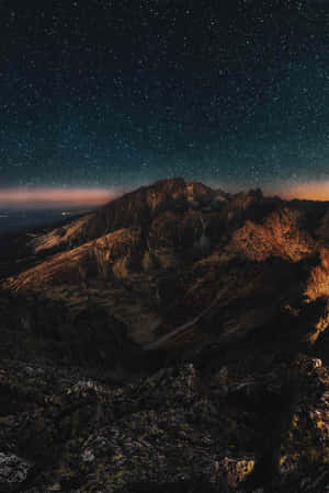 繁星夜空映襯崎嶇山峰，岩石上泛著橙色光芒 — Oppo Pad 壁紙