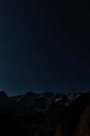 繁星點點的夜空下，黑暗的山脈，山頂有雪，下方有森林。 — 夜空 壁紙