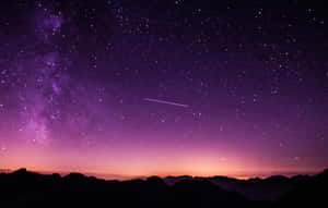 紫色和粉紅色的夜空，星星和流星在山巒剪影之上