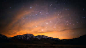 在星空夜空下，帶有發光橙色極光雲的雪山山脈。 — 星星 壁紙