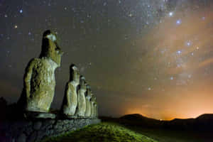 一排古代摩艾石像在星空下，銀河可見。 — 堀與宮村 壁紙