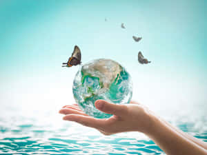 雙手捧著一個玻璃地球儀，蝴蝶在水面上方飛舞。