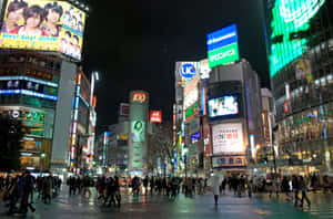 夜晚的東京城市街道，霓虹燈招牌和人群在雨中行走。 — MacBook Pro M2 壁紙