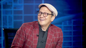 穿著紅色格紋外套和帽子的男子在訪問中微笑。