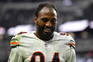 NFL球員94號在夜間穿著骯髒的白色球衣微笑。
