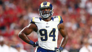 NFL美式足球運動員穿著公羊隊94號球衣，在夜間比賽中站在球場上。