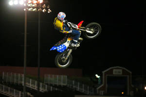 越野電單車手在夜間體育場燈光下空中跳躍