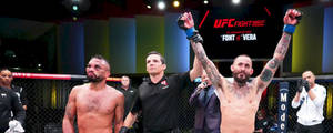 UFC拳手在八角籠中舉起拳頭慶祝勝利。