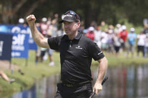 高爾夫球手在陽光普照、近水的高爾夫球場上舉起拳頭慶祝勝利。