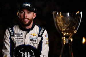 NASCAR車手在黑暗工作室環境中與獎盃合影