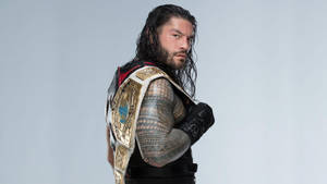 摔角手 Roman Reigns 佩戴冠軍腰帶和黑色裝備，身上有紋身。