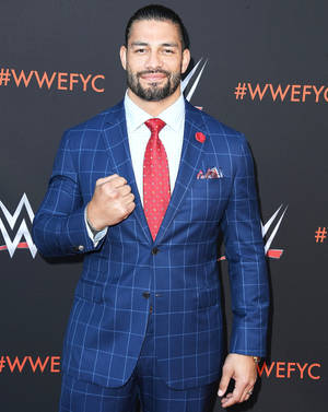 Roman Reigns在WWE活動中身穿藍色格紋西裝和紅色領帶。