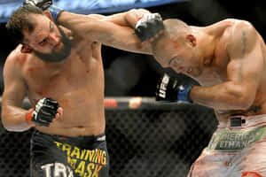 兩名血跡斑斑的MMA拳手在八角鐵籠中互相攻擊。 — 3:2 壁紙