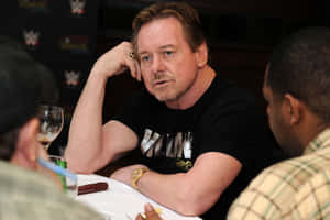 WWE活動桌上穿黑襯衫戴金錶的男子