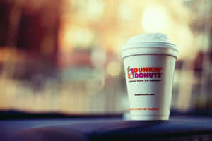 Dunkin' Donuts咖啡杯在黑暗表面上，背後有模糊的溫暖燈光。