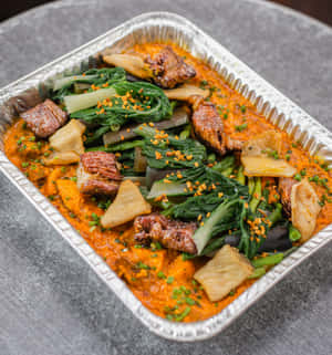 一個裝有橙色燉菜、青菜、肉同豆腐嘅鋁箔盤。 — Galaxy Z Flip7 FE 壁紙