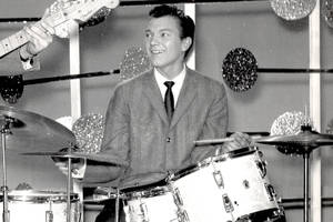 微笑的音樂家在閃爍的1960年代錄音室中與結他手一起打鼓。