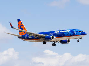 Sun Country Airlines 噴射機放下起落架，在部分多雲的天空中低飛。