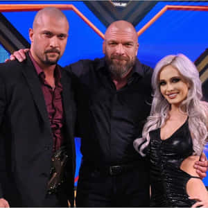 三位WWE摔角手在燈光明亮的舞台上一起擺姿勢。 — 施嘉莉·祖安遜 壁紙