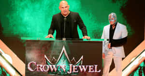 兩位WWE摔角手在Crown Jewel活動頒獎台上，一位戴面具，一位沒戴面具。