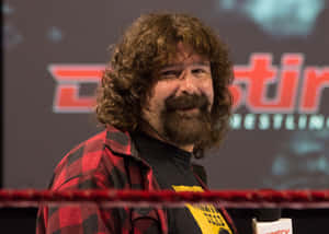 留鬍鬚和捲髮的摔角手，身穿紅色格仔恤衫，在摔角場內。 — WWE GIF 壁紙