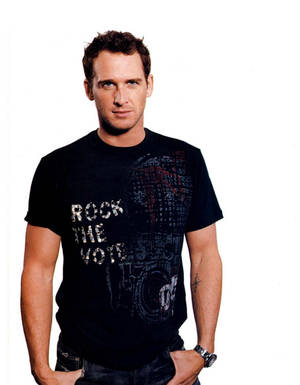 身穿黑色「rock the vote」T恤的男子，雙手插袋站立。